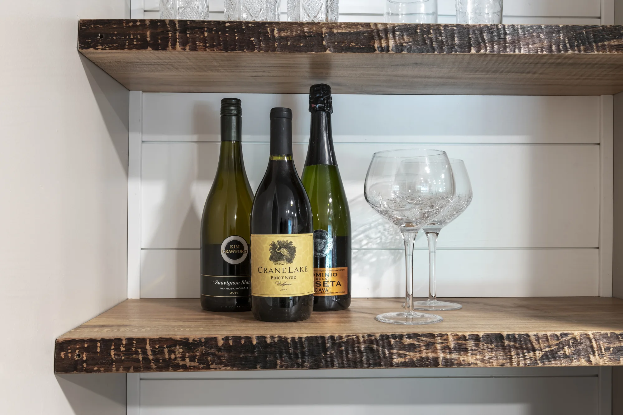 Natural wood display shelves with wine bottles and glasses